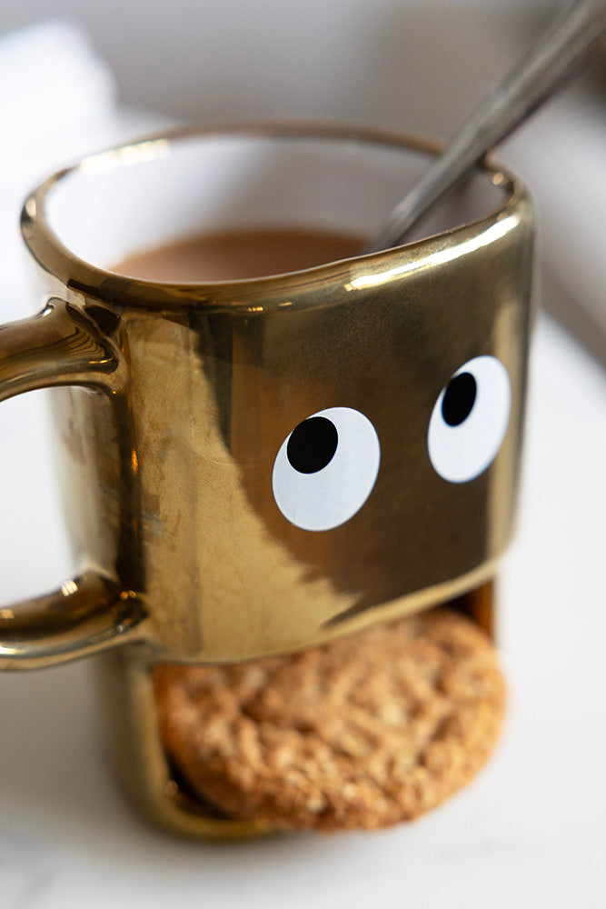 Tasse à biscuits dorés tenant un visage