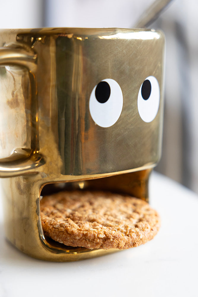 Tasse à biscuits dorés tenant un visage