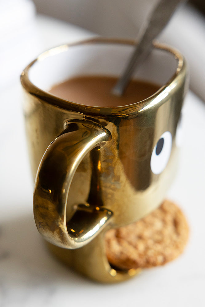 Tasse à biscuits dorés tenant un visage