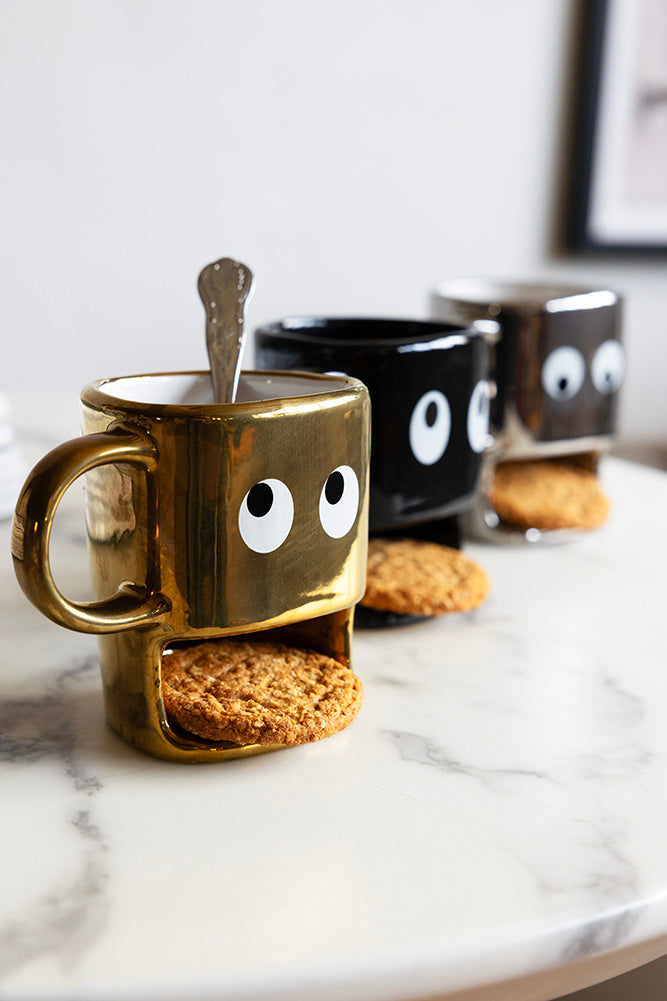 Tasse à biscuits dorés tenant un visage